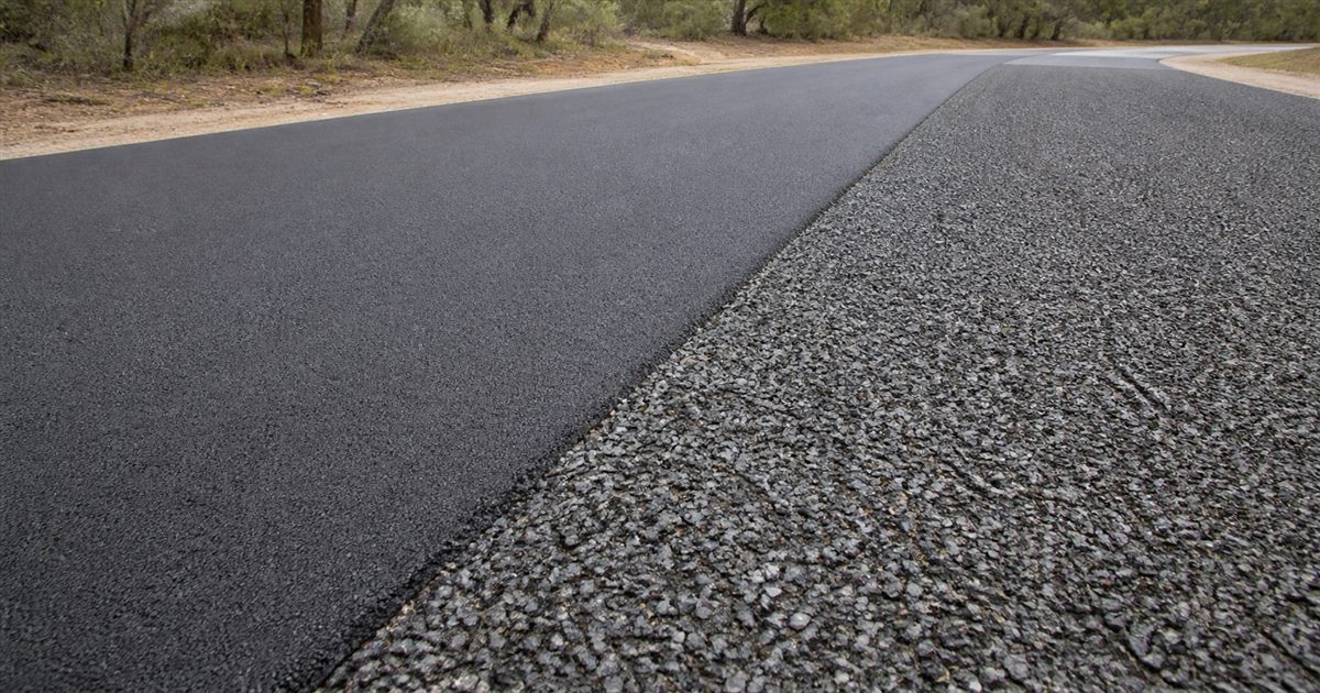Smooth asphalt pavement beside a coarse sprayed bitumen chip-seal surface