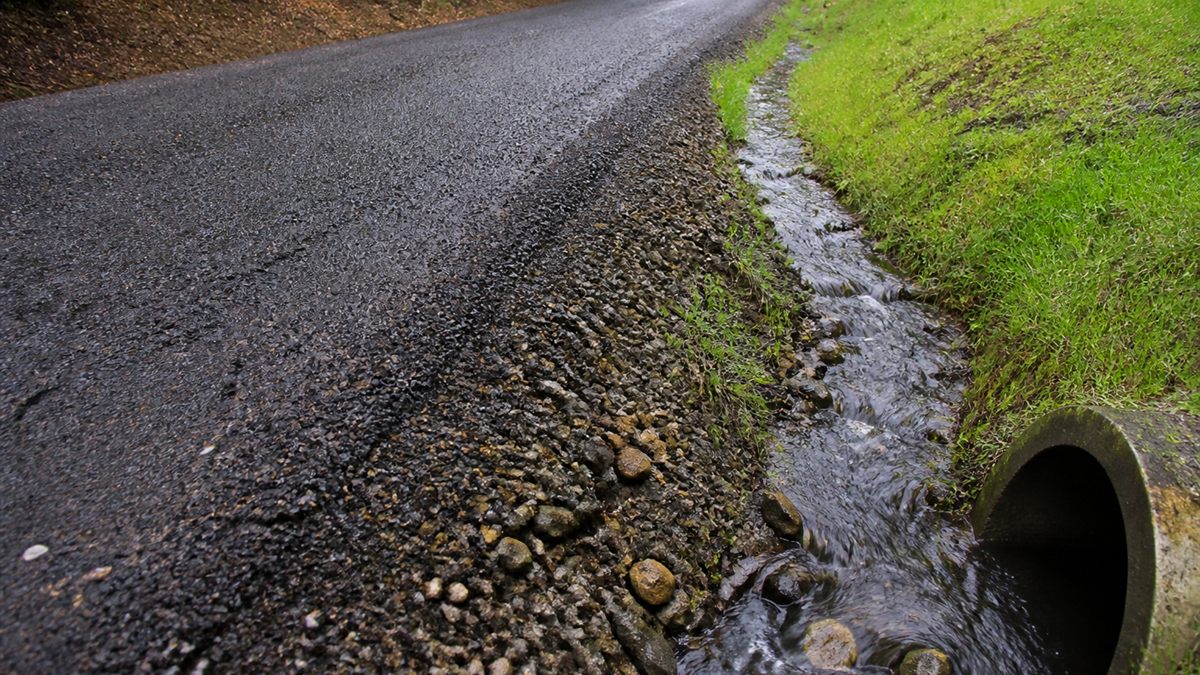 Drainage swale and culvert carrying rainwater away from a chip-seal driveway